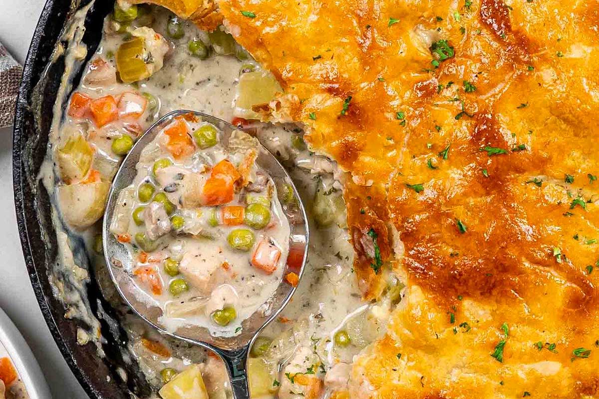Chicken pot pie in a skillet with a spoon.