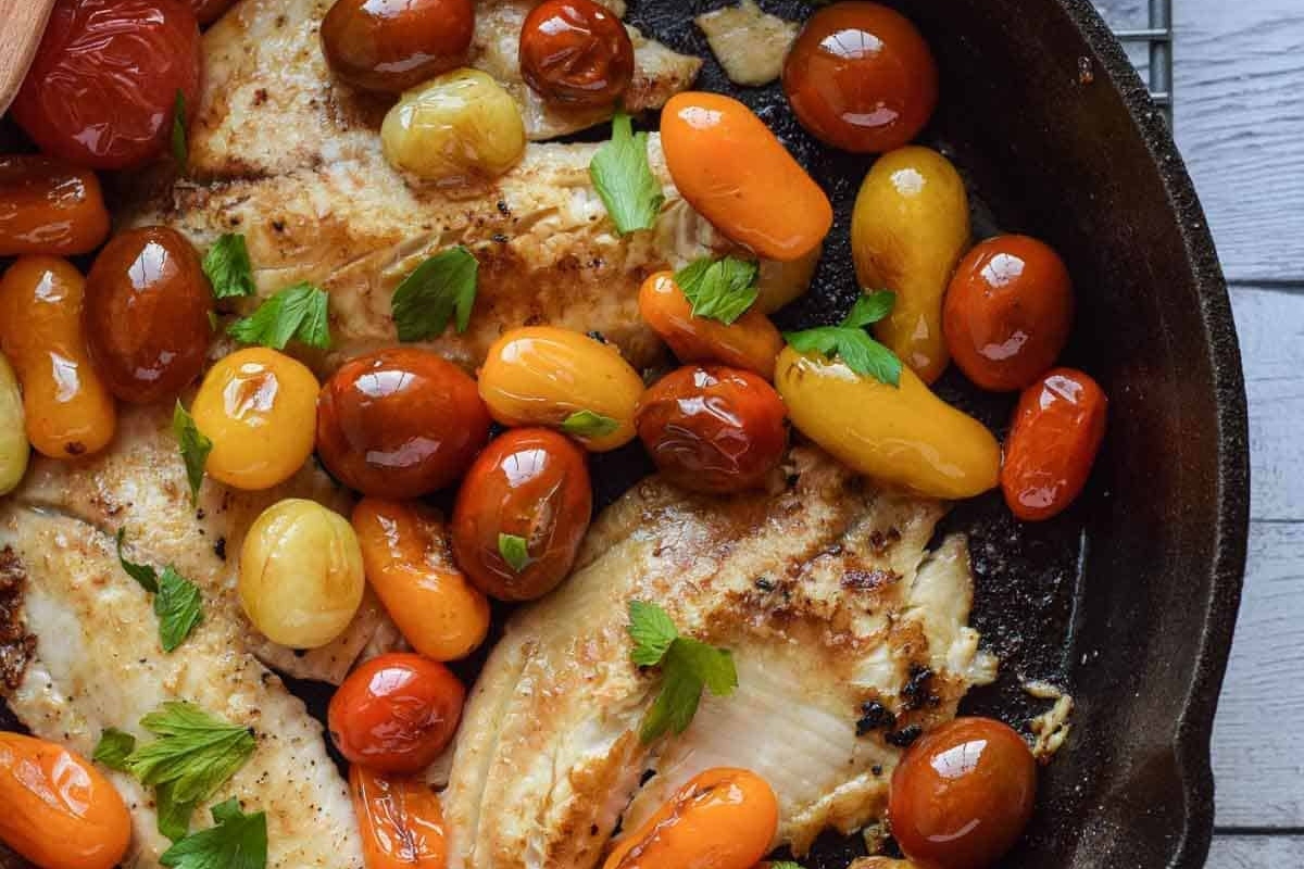 Grilled chicken with tomatoes and herbs in a skillet.