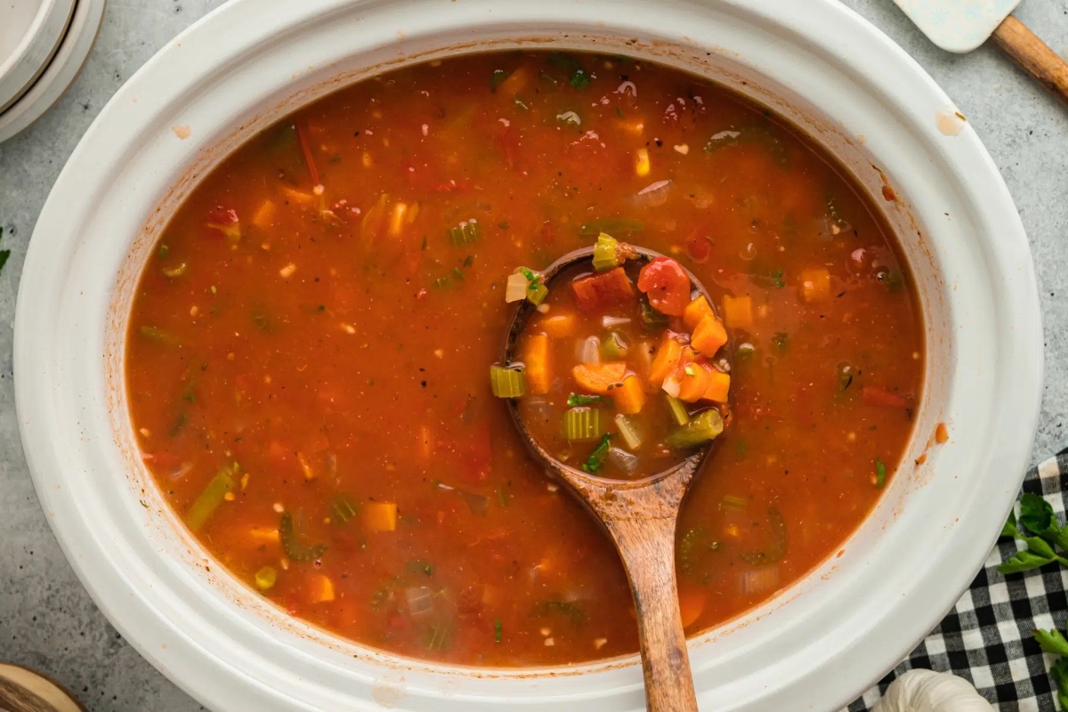 A bowl of tomato soup with a wooden spoon, perfect for incorporating frozen mixed vegetables into delicious recipes.