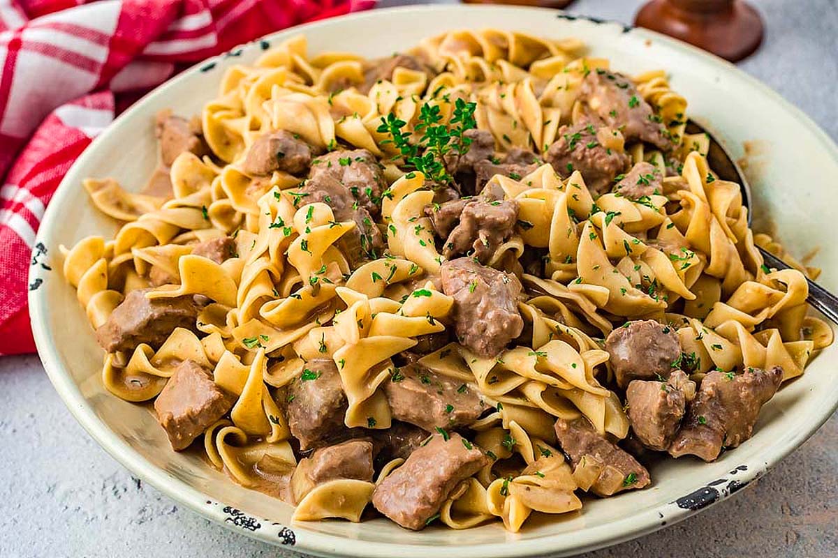 A bowl of pasta with meat and herbs.
