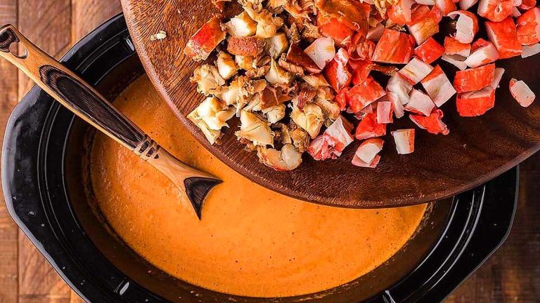 A crock pot with a bowl of clam chowder, perfect for tomato recipes, and a wooden spoon.