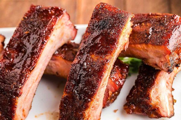 Mouthwatering BBQ ribs on a white plate, tantalizingly awaiting eager taste buds.