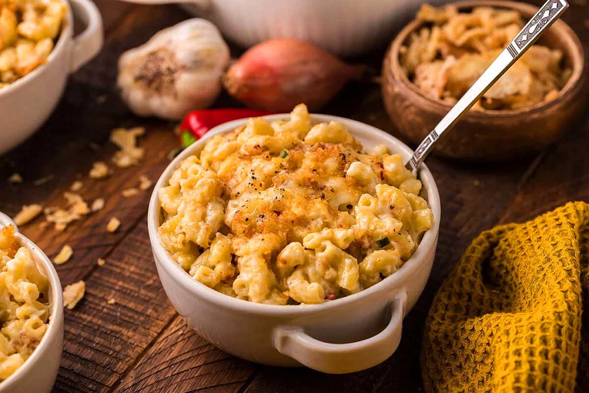 Macaroni and cheese served in bowls at a rustic wooden table, perfect for pub and bar food enthusiasts.