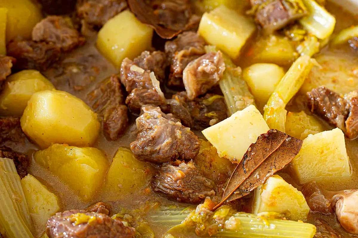A stew with meat, potatoes and celery.