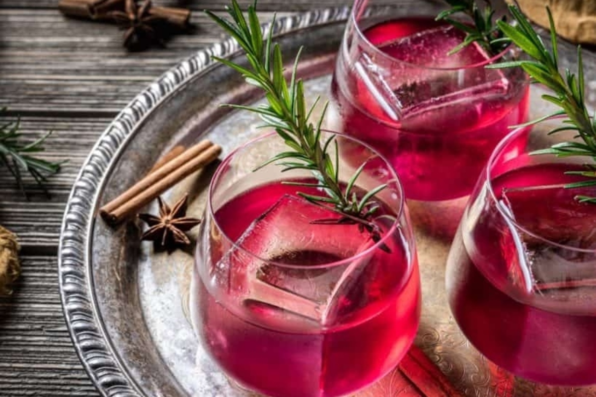 Recipes with Pomegranate to Add Color to the Season 11 A glass of red wine infused with cinnamon sticks and rosemary sprigs, perfect for cozy evenings by the fire.