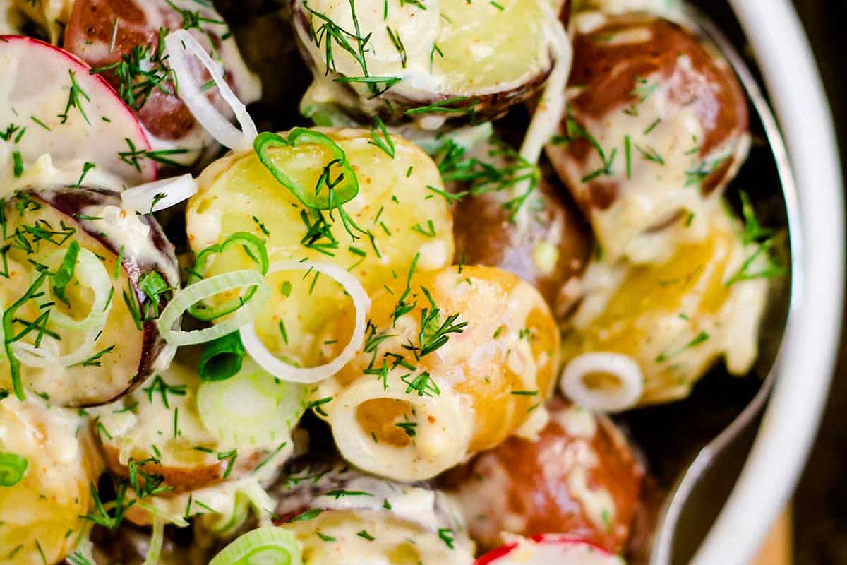 A bowl of potato salad with radishes and dill.