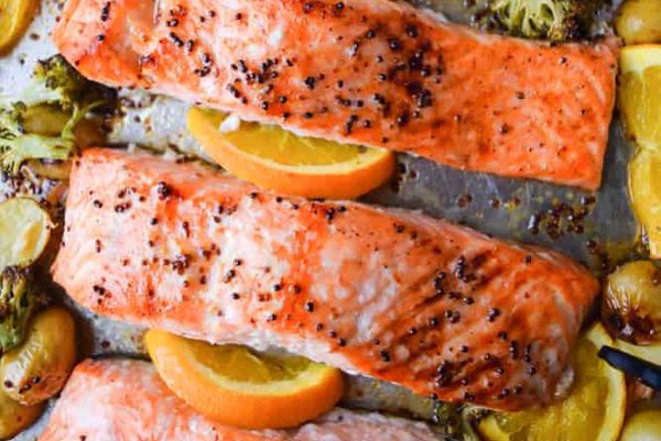 Salmon with oranges and broccoli on a baking sheet.