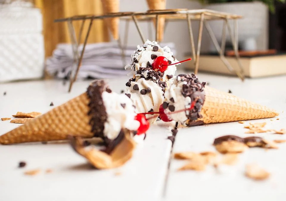 Italian Dessert: Ice cream cones with chocolate and cherry toppings on a table.