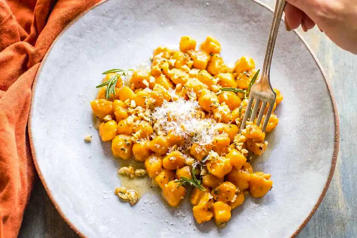 A delectable plate of pumpkin gnocchi, ready to be enjoyed with a fork.