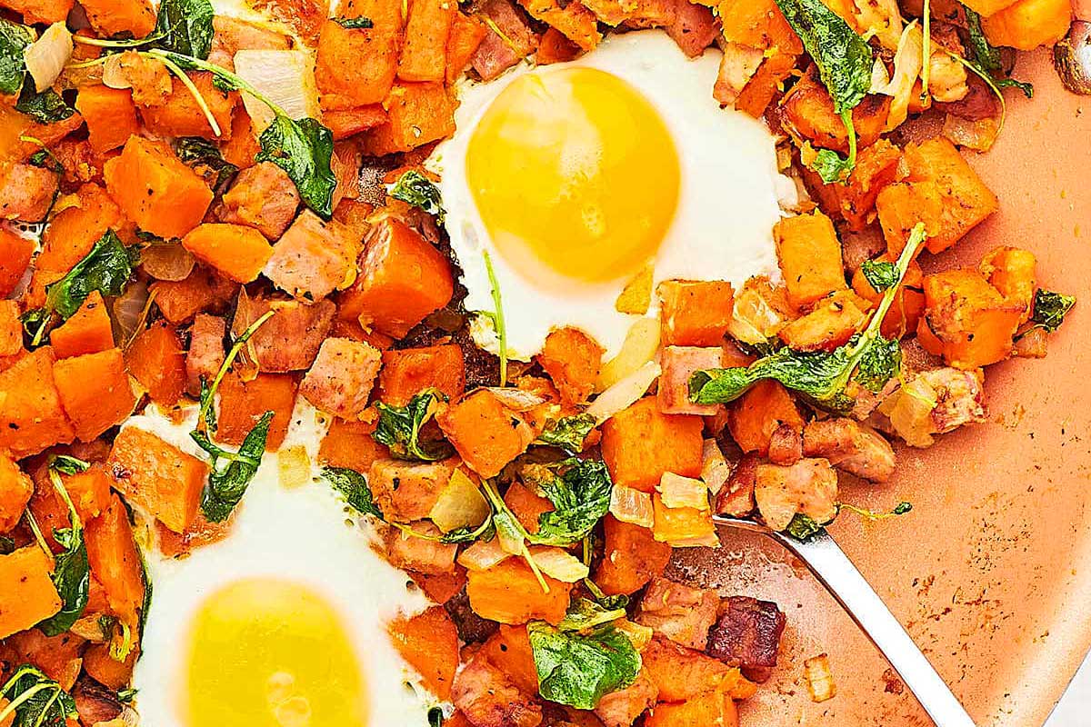 Sweet potato hash with eggs and spinach on a plate.