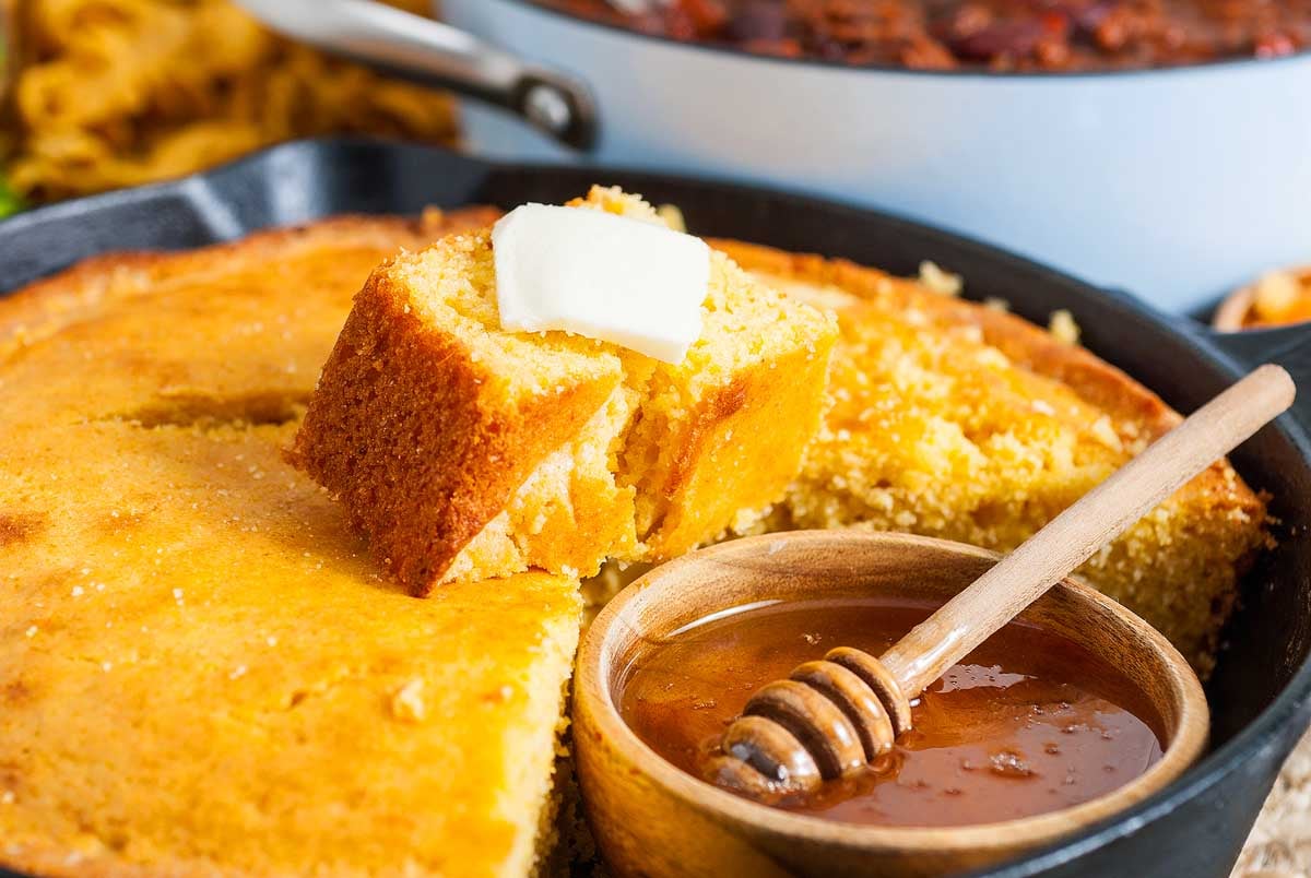 Country style cornbread cooked in a skillet with a drizzle of honey.