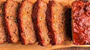 Sliced meatloaf on a wooden cutting board.