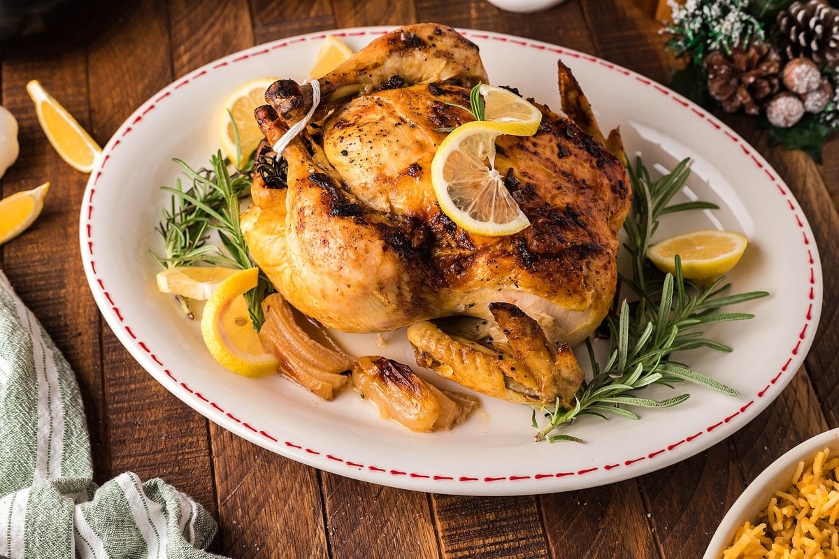 Thanksgiving main dish featuring succulent roasted chicken seasoned with fragrant rosemary and zesty lemons, elegantly presented on a plate. This is one of the best Thanksgiving main dishes.