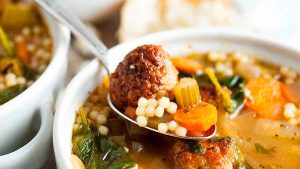 An Italian bowl of soup with meatballs and vegetables.