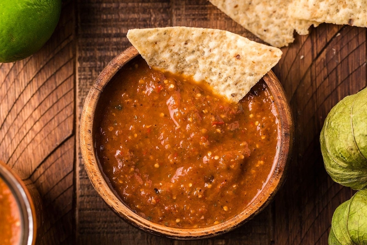 A bowl of salsa and tortilla chips on a wooden table.