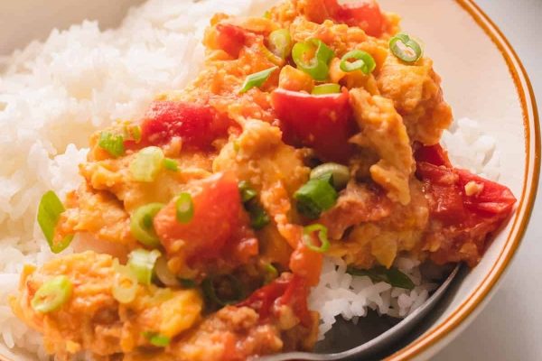 An appetizing recipe featuring a bowl of rice with flavorful chicken and succulent tomatoes, perfect for utilizing pantry staples.