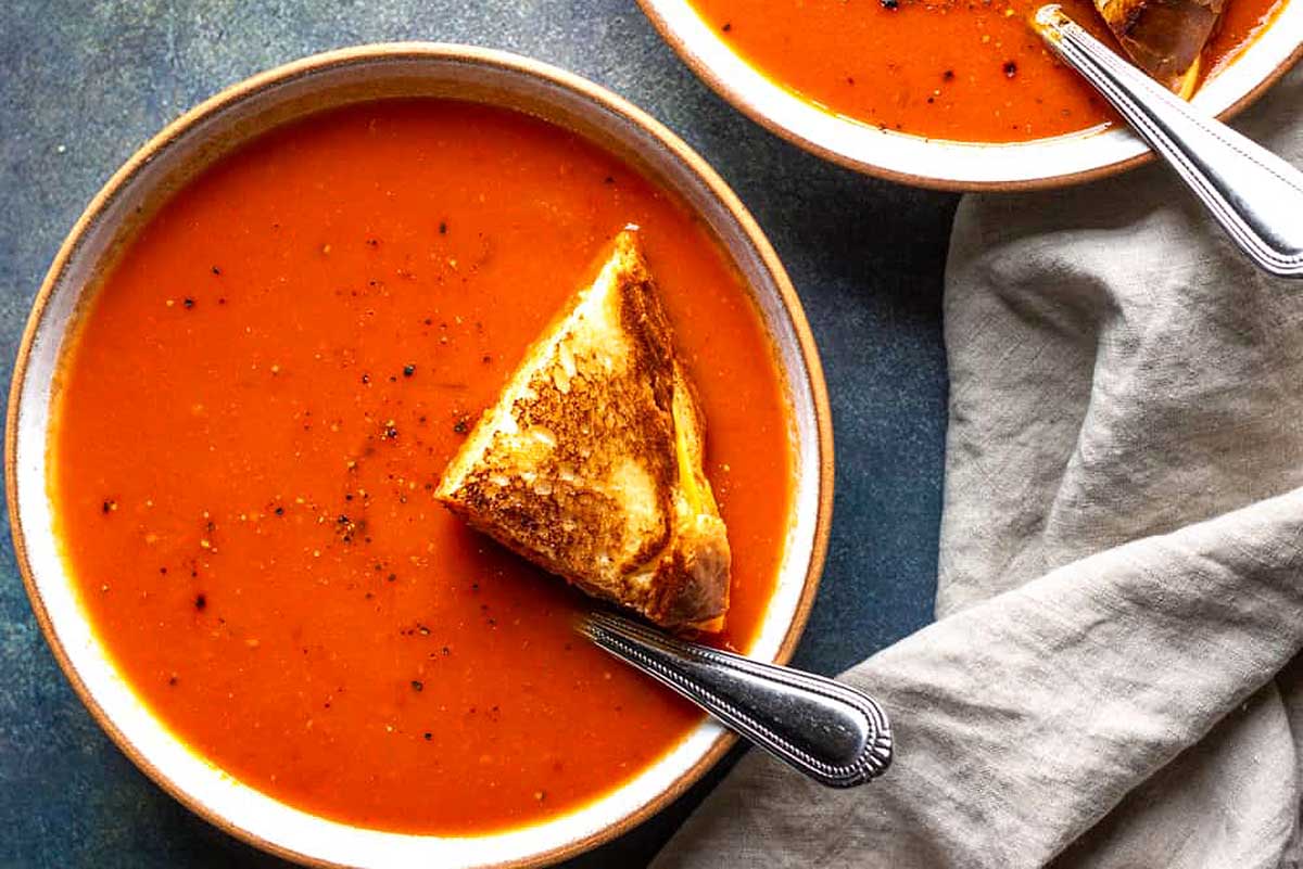 A bowl of tomato soup with a slice of toasted bread.