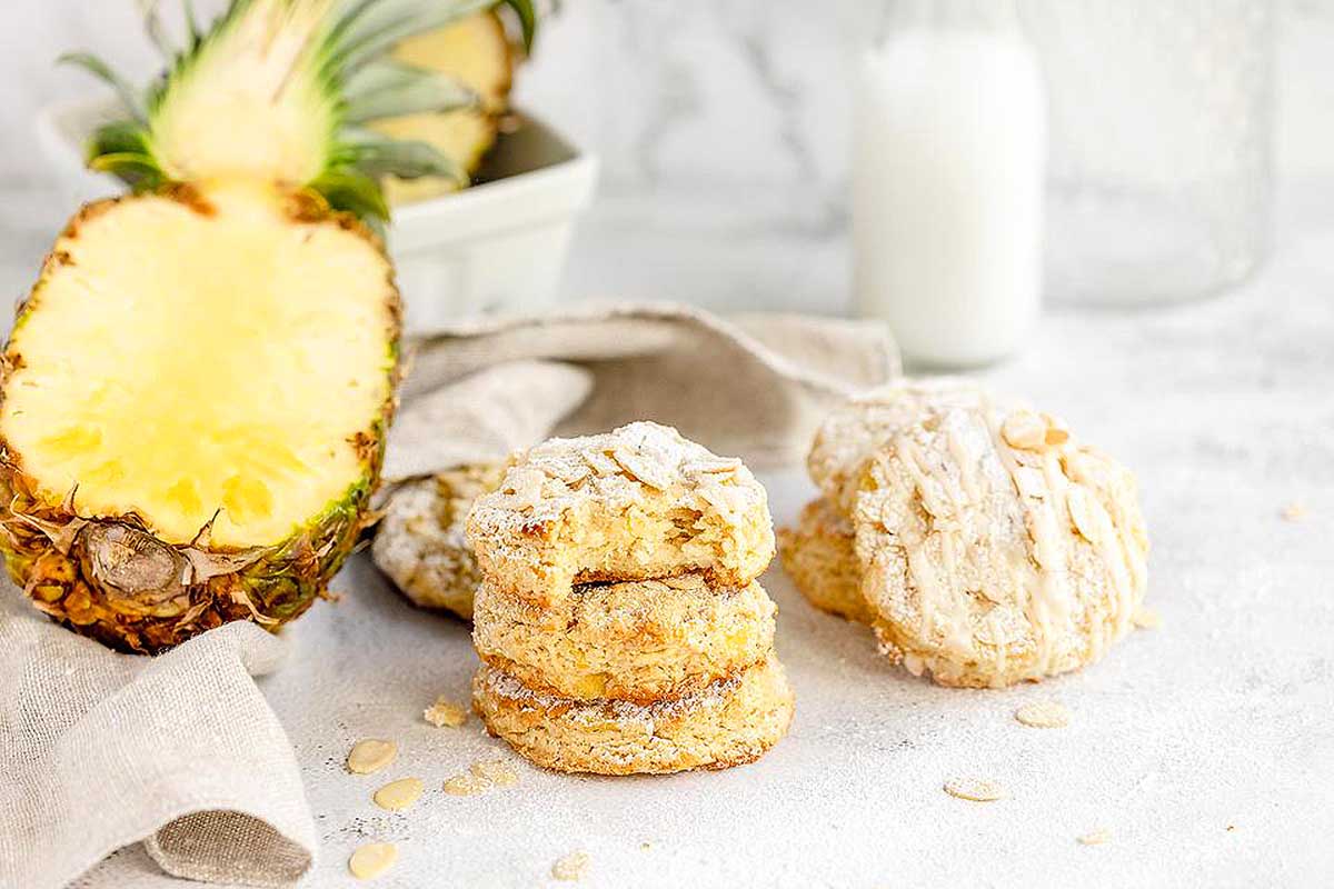 Hawaiian inspired pineapple scones on a white table next to a glass of milk.