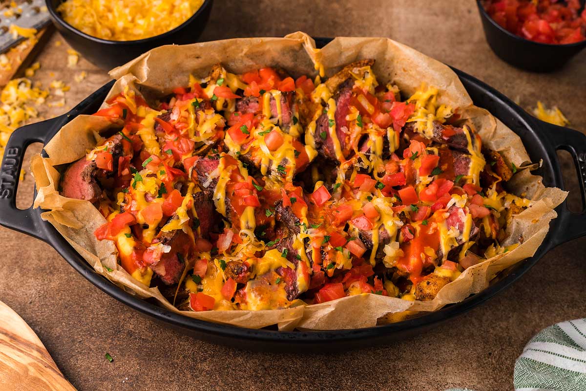 Delicious nachos prepared in a cast iron skillet with the addition of crispy corn and flavorful tomatoes.
