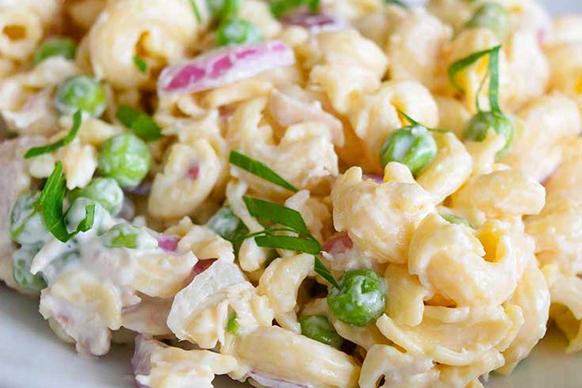 A bowl of pasta salad with peas.