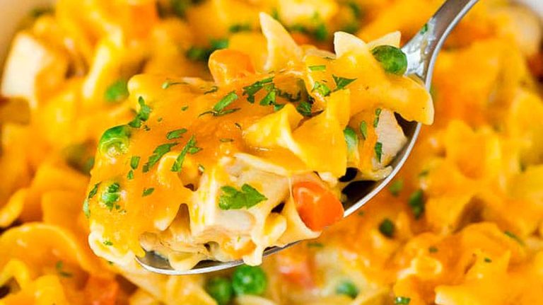 A spoonful of leftover turkey noodle casserole in a white dish.
