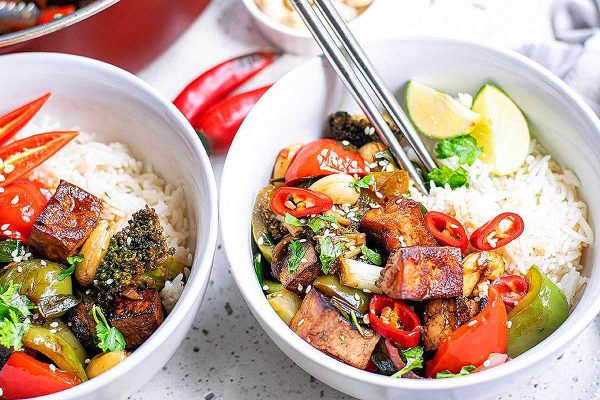 Two bowls with rice and vegetables in them.