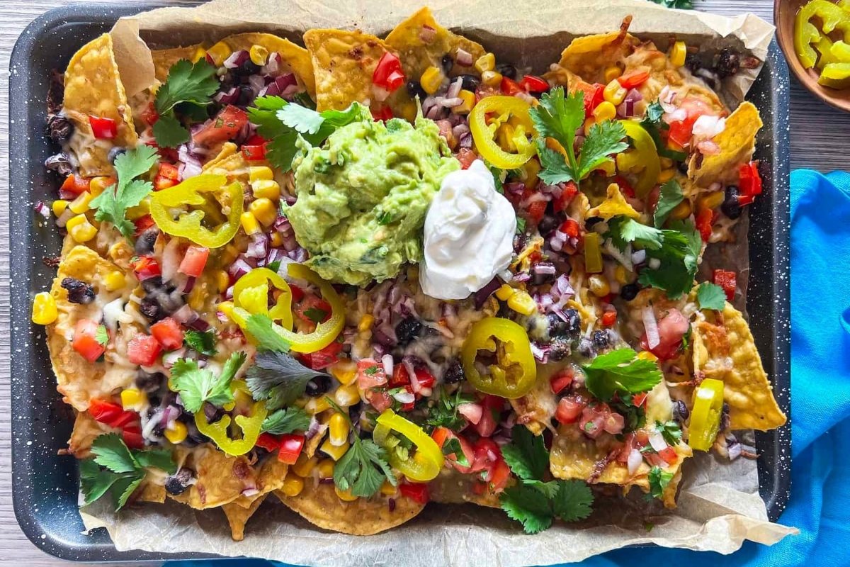 Mexican nachos on a tray with guacamole and sour cream.