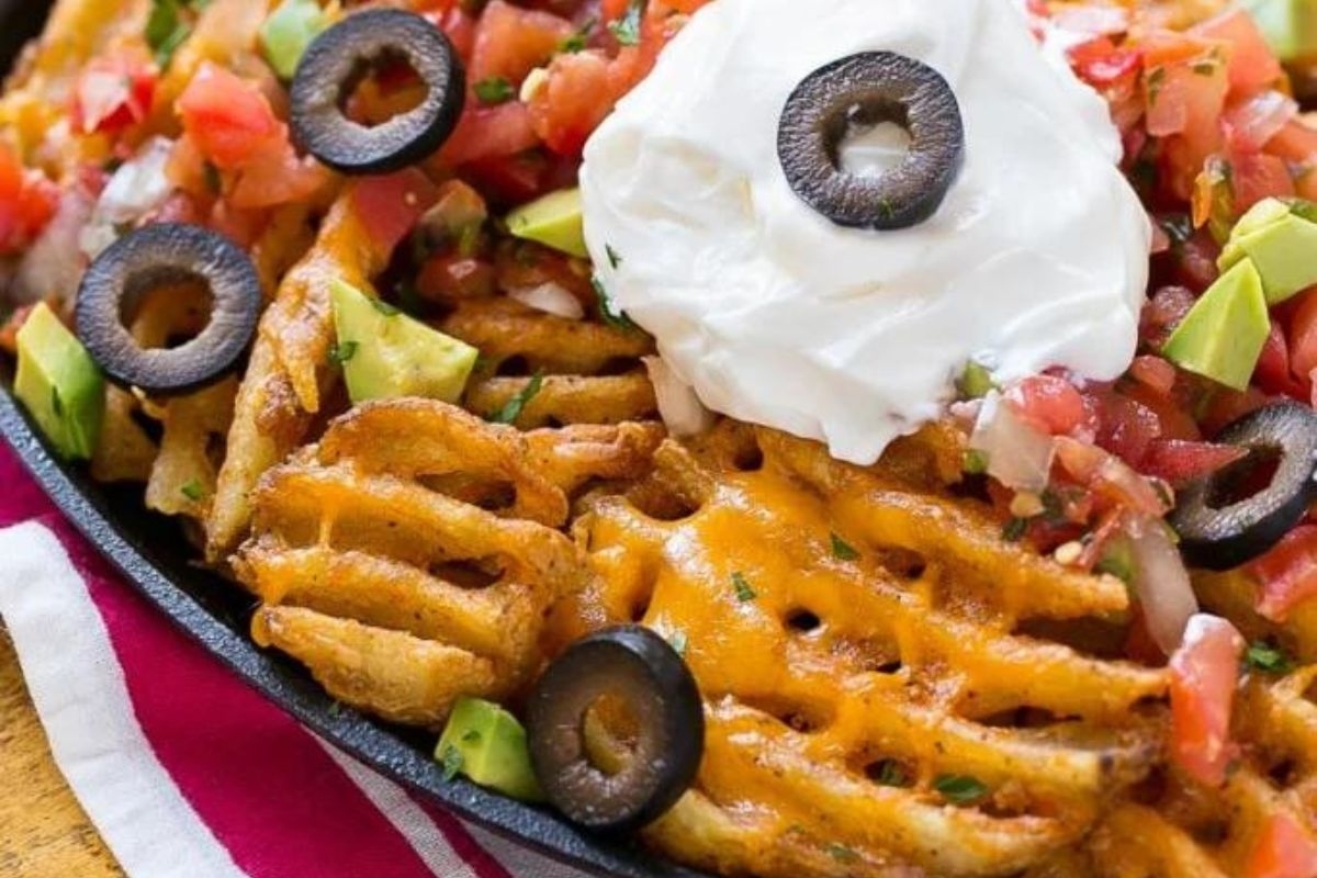 Mexican nachos in a skillet with sour cream and avocado.