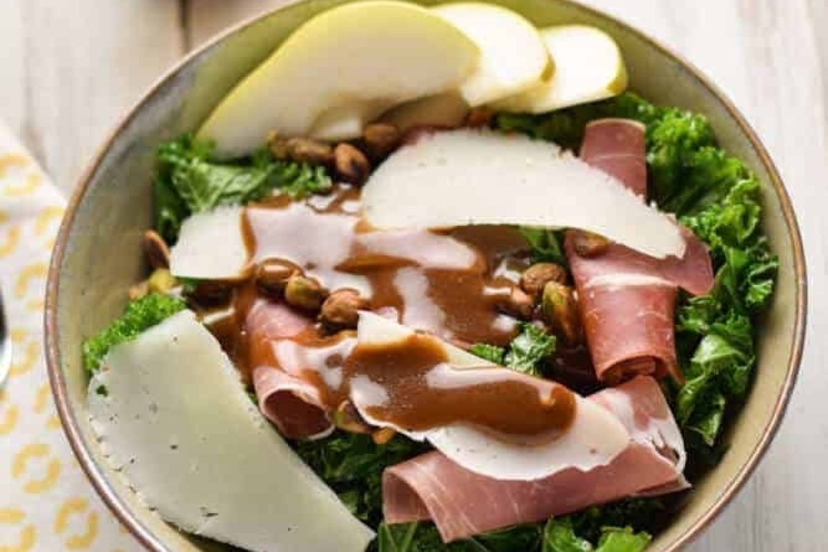 A bowl of kale salad with ham and cheese.