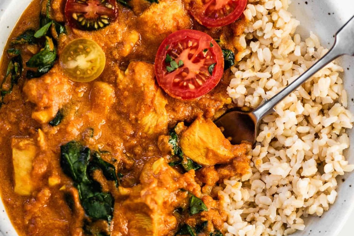 A bowl of chicken curry with rice and tomatoes, perfect for those craving delicious curry recipes.