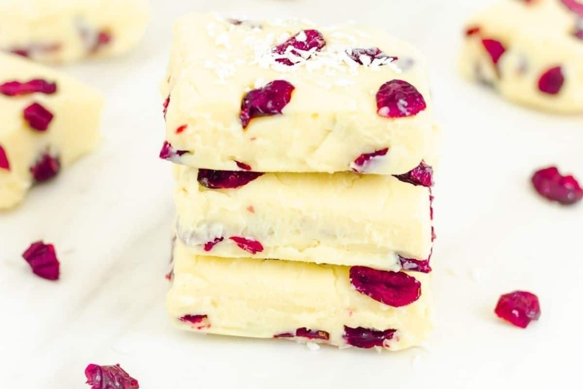 A stack of cranberry fudge, perfect for Christmas recipes, on a white surface.
