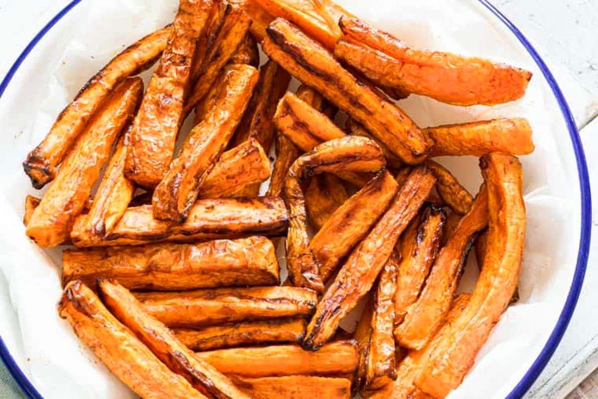 Sweet potato fries artfully presented in a bowl on a wooden table, showcasing delicious fry recipes.