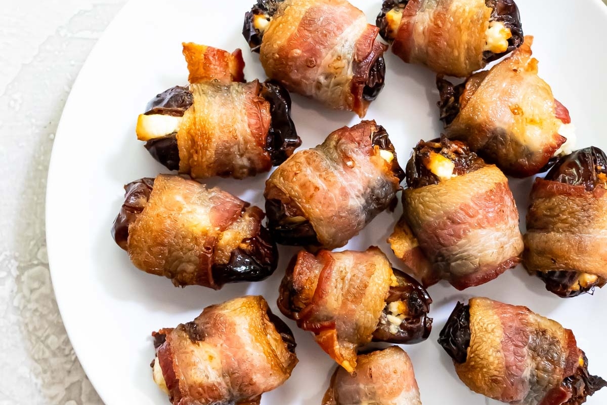 Goat cheese-stuffed bacon wrapped dates on a plate.