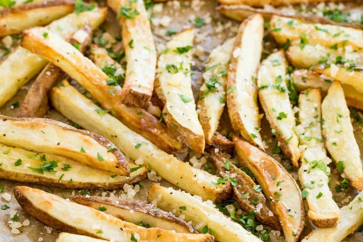 A baking sheet with truffle oil recipes and french fries served with parsley.