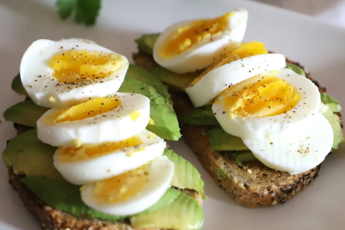 A healthy breakfast of two slices of toast topped with eggs and avocado, packed with high protein.