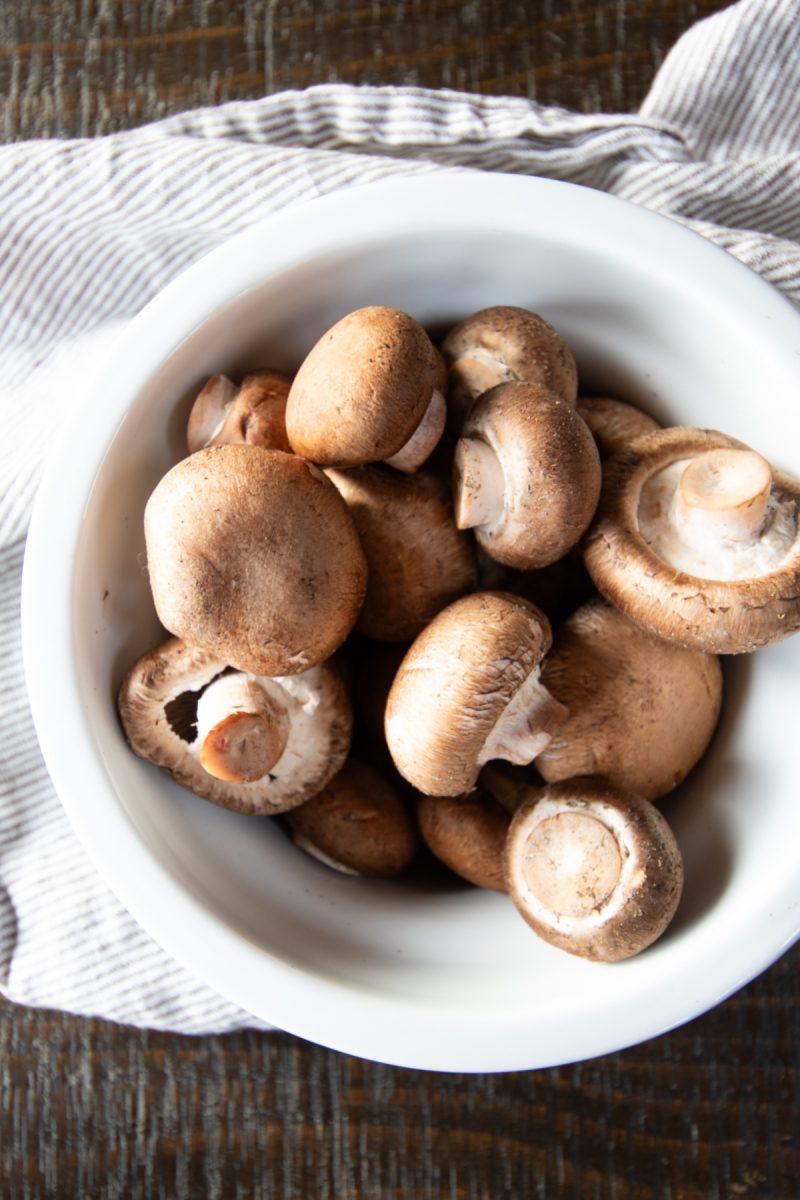 Air fryer mushrooms in a white bowl on a wooden table.