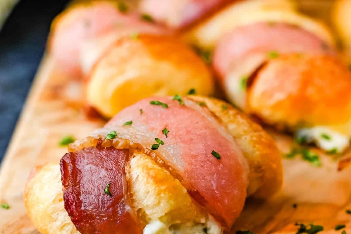48 Easy Bite-Sized Appetizers Party Guests Will Love 33 Game day appetizers featuring delicious bacon and cheese rolls presented on a cutting board.