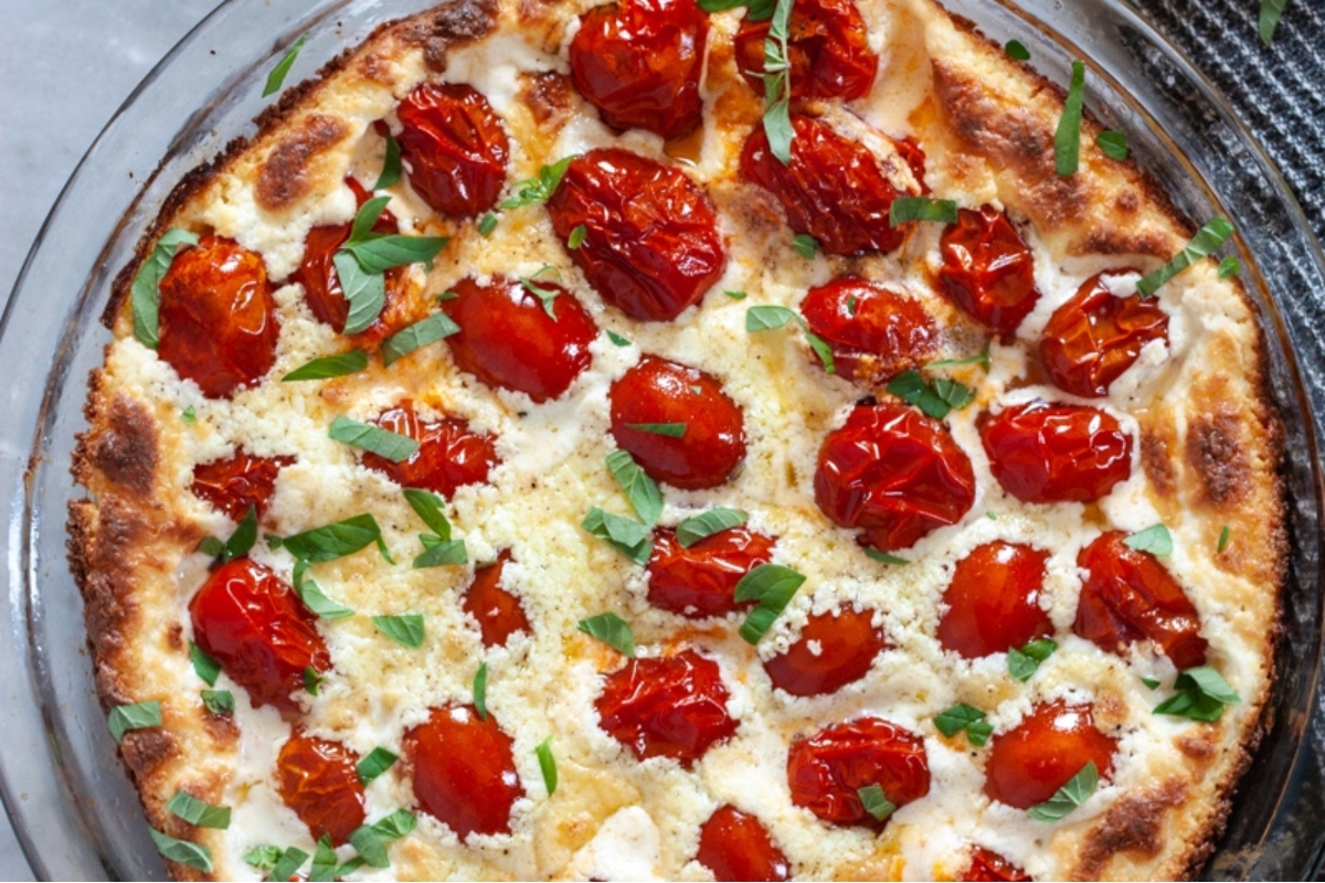 A goat cheese pizza with tomatoes in a glass dish.