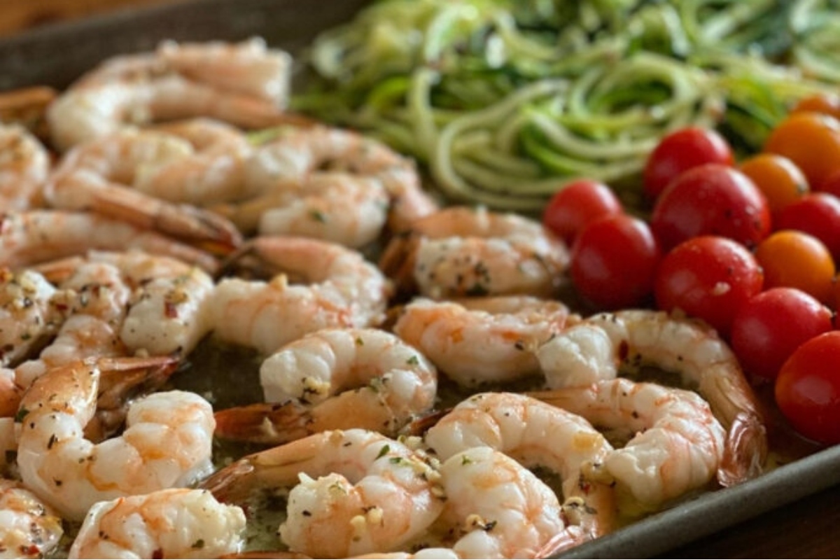 Loaded with vegetables, this dinner features a delicious combination of shrimp, zucchini, and tomatoes on a baking sheet.
