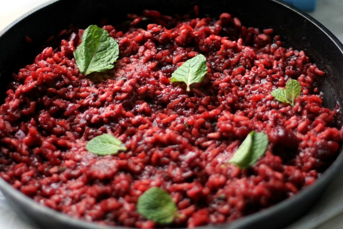 A vibrant and nutritious dish of beetroot rice cooked in a skillet, garnished with fresh mint sprigs. Perfect for those seeking delicious beet recipes.