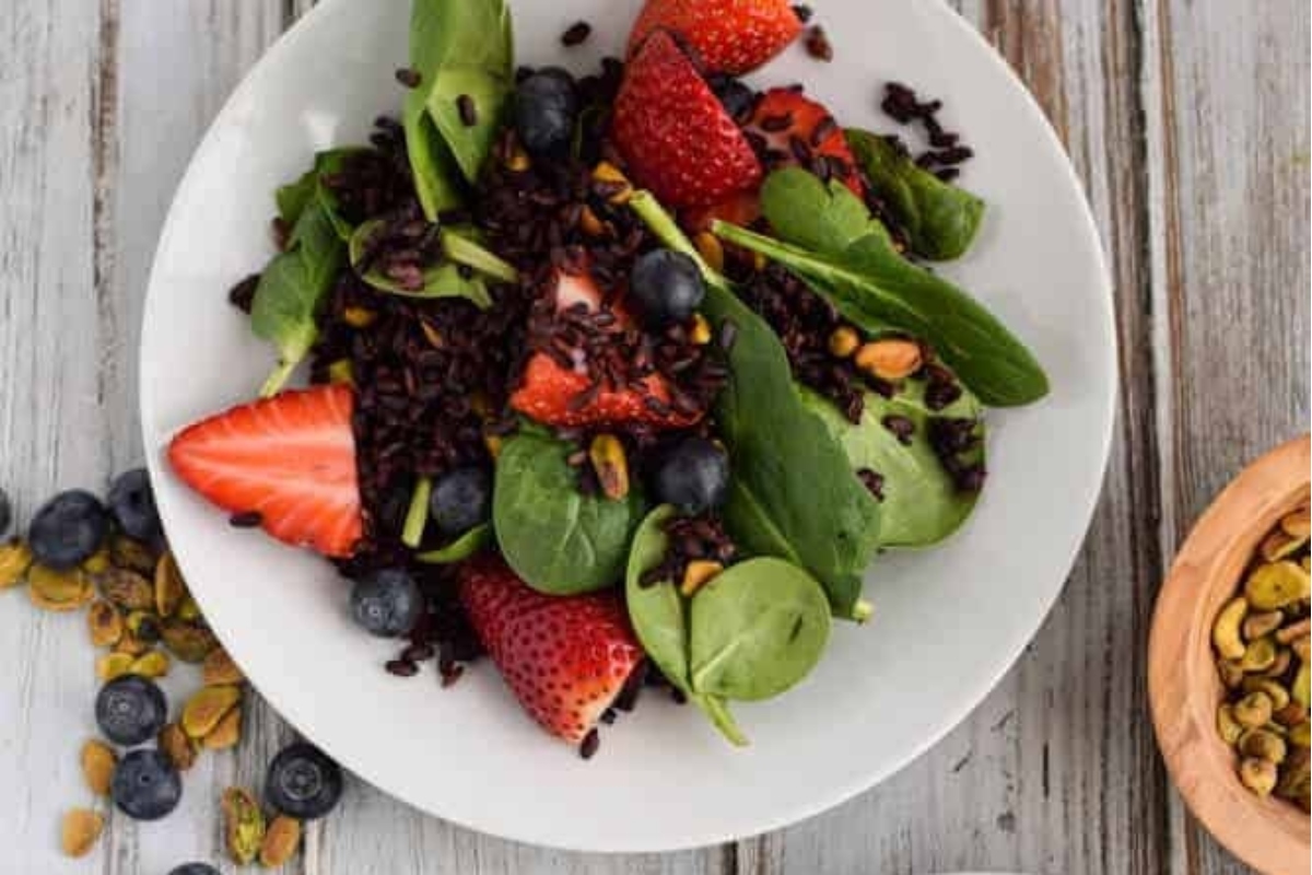 Black rice salad with strawberries, pistachios, and spinach.