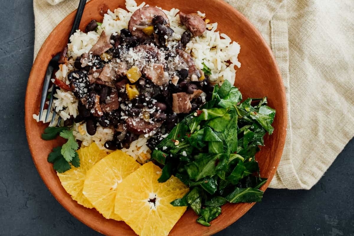Recipes for a black bean and rice stew with orange slices on a plate.