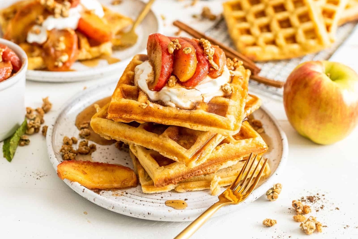 A delightful waffle recipe garnished with fresh apples and fluffy whipped cream.