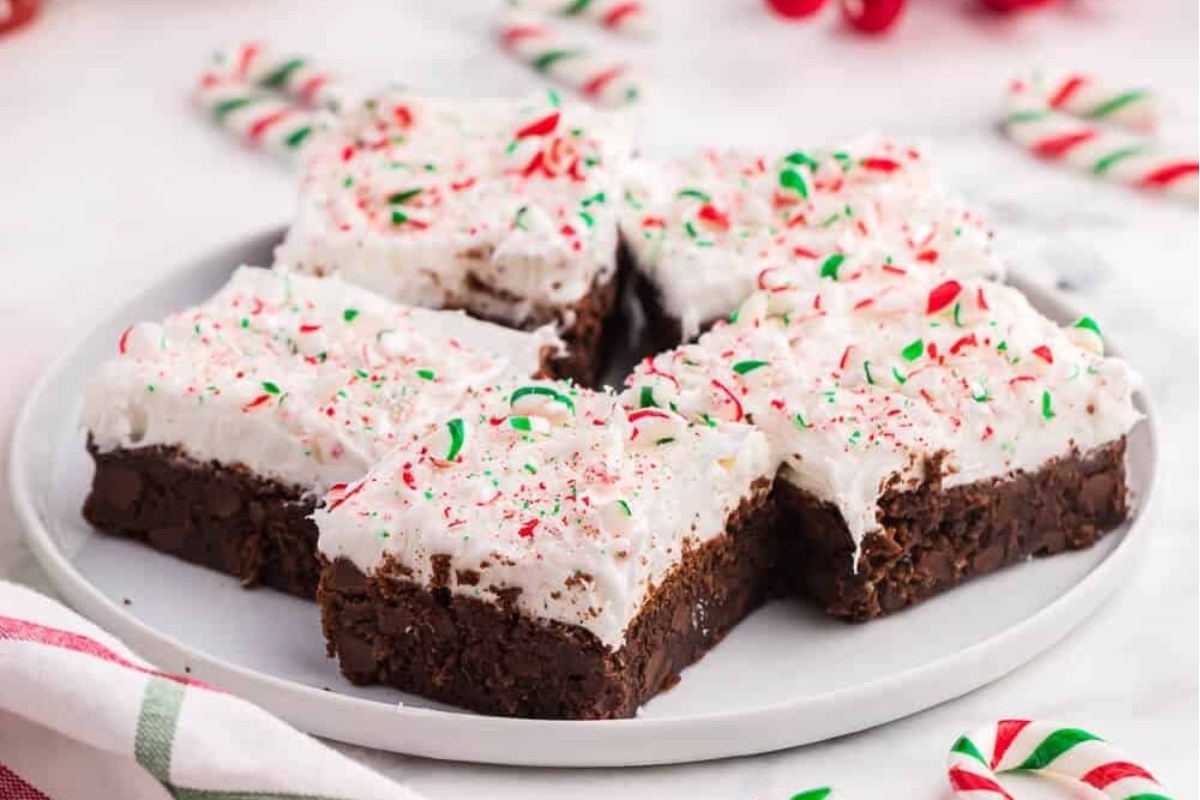 A plate of chocolate brownies with whipped cream and candy canes, perfect for making delicious candy cane recipes.