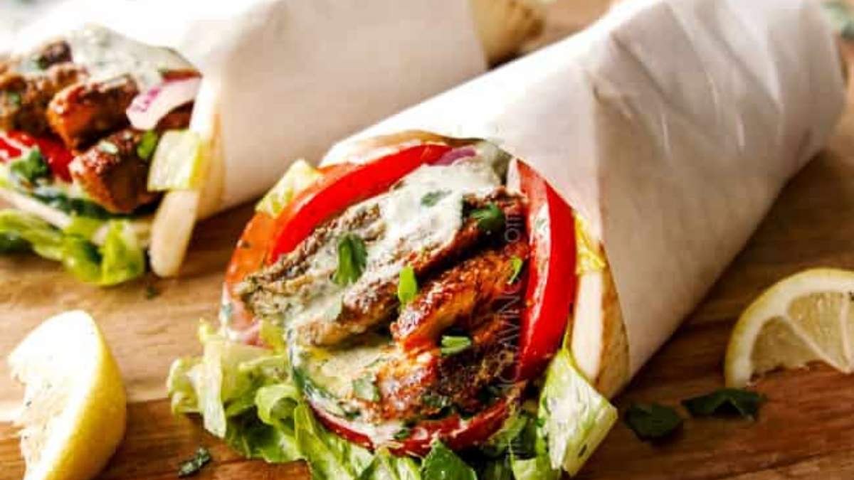 Two pita wraps on a wooden cutting board.