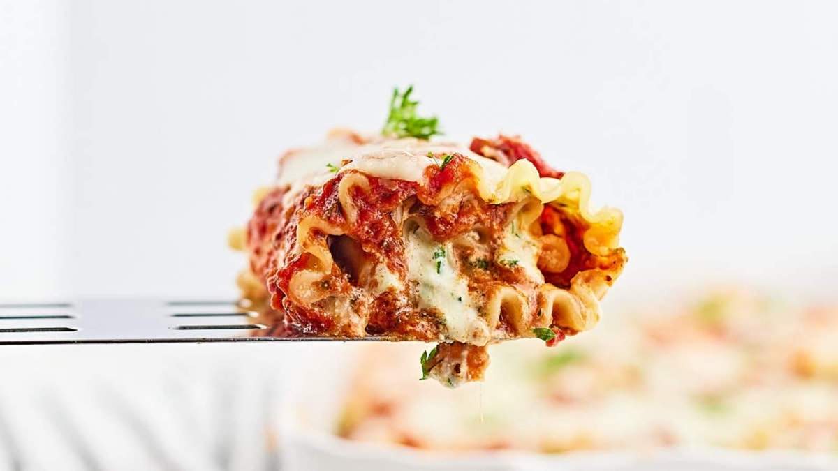 A fork is being used to pick up a piece of lasagna, the ultimate comfort food.