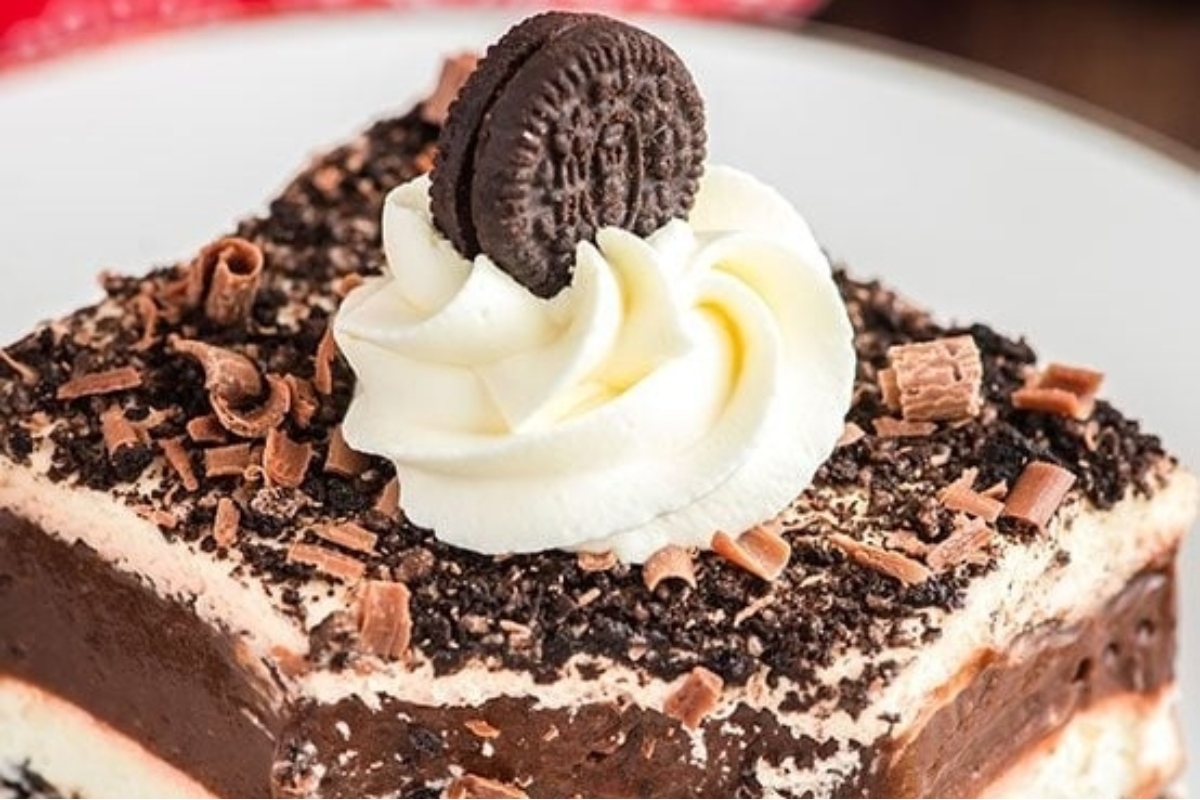 A recipes oreo ice cream cake is topped with whipped cream and oreos for a delectable dessert treat.