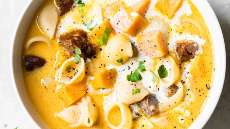 A bowl of potato soup with noodles and meat in it.