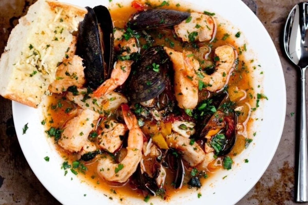 A delicious seafood stew with bread and breadsticks.