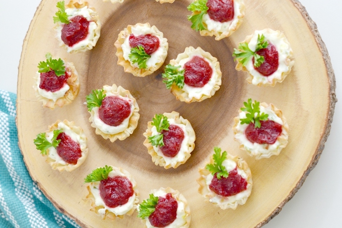 Cheesy cranberry cheesecake bites on a wooden plate.